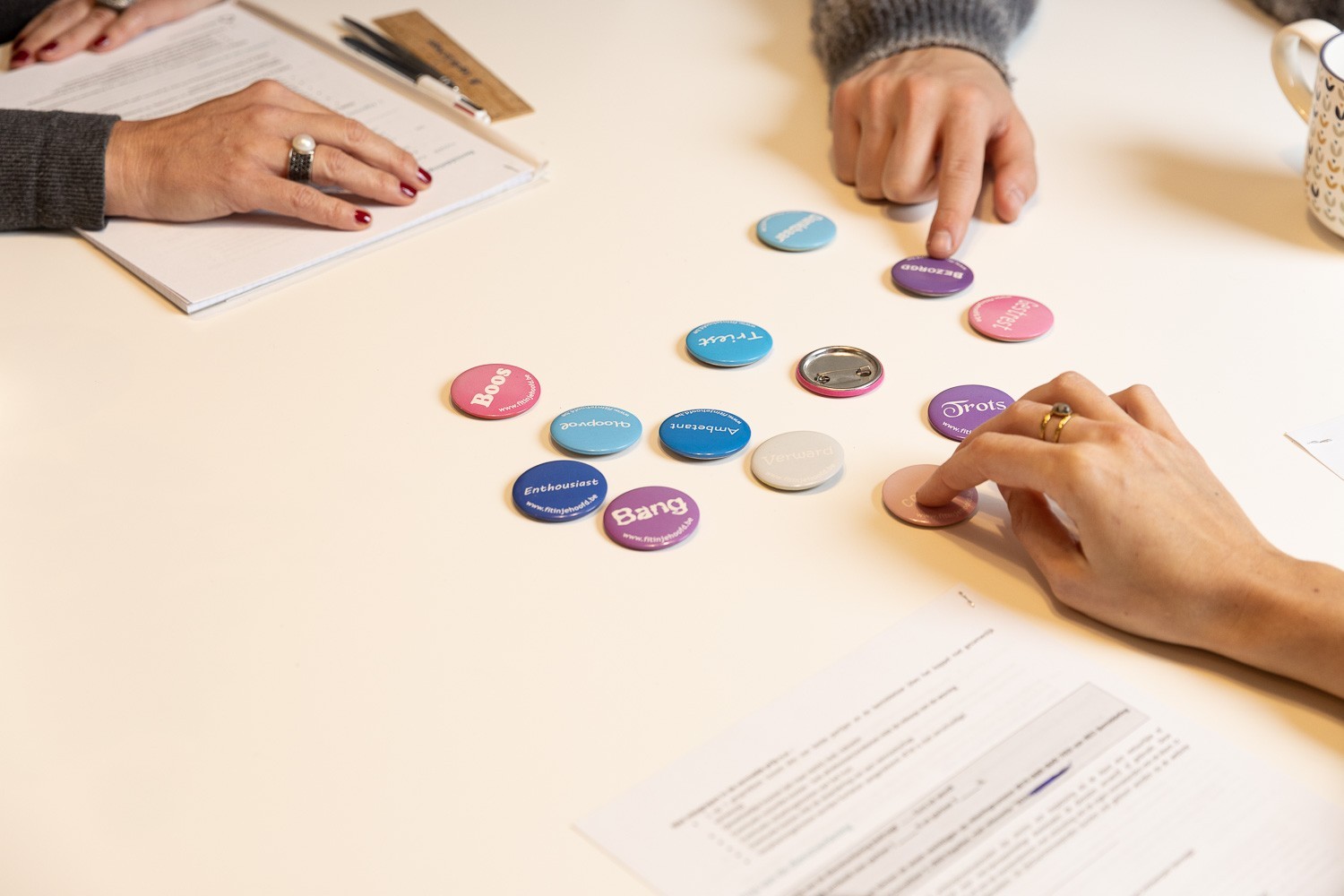 Een tafel met daarop buttons met drie personen die deze ordenen tijdens een bemiddelingssessie van NEO Bemiddeling Antwerpen
